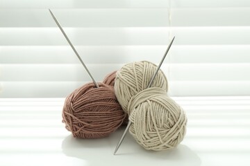 Wall Mural - Skeins of soft yarn and knitting needles on white table indoors