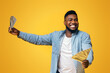 © Prostock-studio - Big Win. Overjoyed African American Man Holding A Lot Of Money In Both Hands On Yellow Background, Panorama