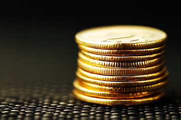 A stack of shiny gold coins glistens on a dark textured surface, representing wealth, prosperity, and financial success.