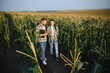 © Serhii - irrigation corn. two farmers work in field with corn. agriculture irrigation concept. farmers a man and woman work