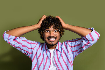 Wall Mural - Photo of funky funny crazy guy with wavy hair dressed striped shirt in glasses show teeth arms on head isolated on khaki color background