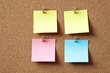 © Artsaba Family - Four blank sticky notes in yellow, pink, and blue colors pinned in a grid pattern on cork board