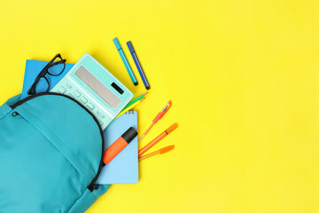 Wall Mural - Light blue backpack and different school supplies on yellow background, flat lay. Space for text