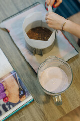 woman is holding glass of whites cream for the cake. fills the cake with cream