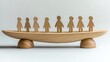© Mohammed - A wooden balance scale with carved wooden human figures evenly distributed, symbolizing equality and teamwork against a minimalist background.