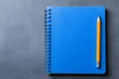 © Elmira - An open blue spiralbound notebook is positioned next to a pencil on a cool grey surface, inviting thoughts and ideas to be recorded