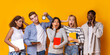 © Prostock-studio - Exams are coming. Stressed group of international students with books holding alarm, yellow background