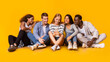 © Prostock-studio - Teens lifestyle. Multiracial group of teenagers sitting on floor and looking at smartphone screen, panorama