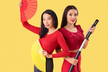 Poster - Young Asian women with fans and katana on yellow background. Chinese New Year celebration