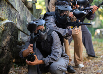 Canvas Print - Group of paintball players aiming and shooting with guns