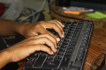 A person typing on a computer keyboard. The person has their hands on the keyboard.