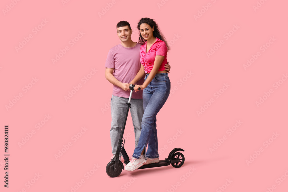 Happy young couple with modern electric kick scooter on pink background