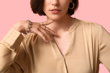 Poster - Beautiful young woman wearing stylish golden jewelry on pink background, closeup