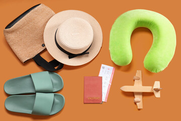 Wall Mural - Travel pillow, passport, ticket and beach accessories on orange background