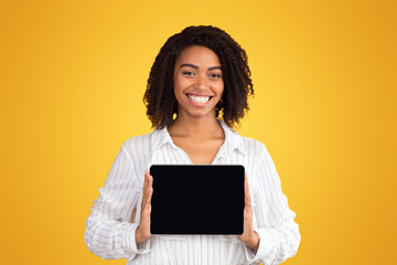 Poster - Black Woman Showing Blank Tablet Computer Screen At Studio Over Yellow Background. Empty space, mockup