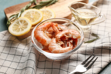 Wall Mural - Glass bowl with tasty boiled shrimps, lemon and rosemary on table