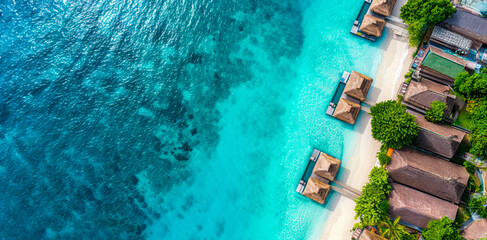 Wall Mural - Aerial view of tropical beach with overwater bungalows during daytime