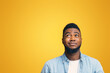 © Prostock-studio - You must be kidding me. Cynical african american guy looking upwards at copy space on yellow studio background, panorama