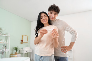 Sticker - Happy young woman with pregnancy test and her husband in bathroom