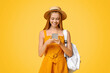 © Prostock-studio - Travel Sim Concept. Young Girl Tourist With Backpack Using Smartphone Over Yellow Background, Texting With Friends Or Browsing Internet