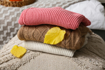 Wall Mural - Folded sweaters with autumn leaves on pouf in bedroom, closeup