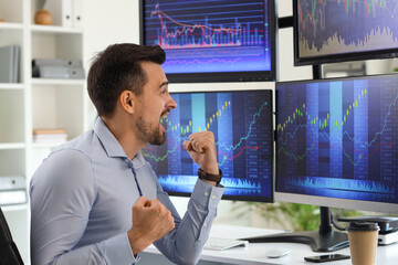 Wall Mural - Happy male trader working at table in office