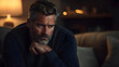 © Siasart Stock - A pensive mature man with a gray beard sits in a dimly lit room and looks off to the side.
