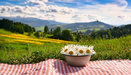 Wall Mural - an idyllic summer picnic scene with a bowl of daisy flowers on a checkered cloth overlooking a lush green landscape