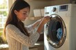© kitipol - A beautiful woman adjusting the settings on a washing machine in a cozy laundry room, enjoying the efficiency of her laundry routine