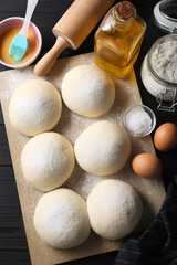 Wall Mural - Raw dough balls, yolk, flour, eggs and rolling pin on black wooden table, top view