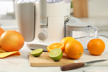 Canvas Print - Modern juicer, oranges and limes on white marble table in kitchen, closeup