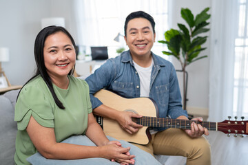 Wall Mural - Portrait of Asian couple spend leisure time in living room in house.