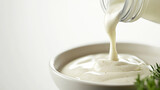 ranch dressing being poured from a bottle into a dipping dish, set against a clean white background