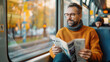 © khonkangrua - A middle-aged man with glasses enjoys reading a newspaper while commuting on a modern, well-lit public transit train.