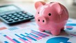 © keks20034 - A pink piggy bank on the background of financial charts and a calculator symbolizes financial management