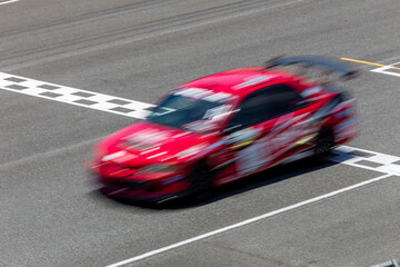 Wall Mural - Motion blur race car racing on speed track, Car race on the international circuit race track crossing start and finish line, Race car crossing start and finish line, Target business achieve victory.