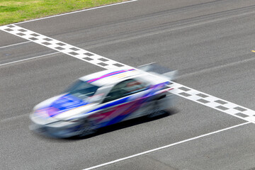 Wall Mural - Motion blur race car racing on speed track, Car race on the international circuit race track crossing start and finish line, Race car crossing start and finish line, Target business achieve victory.