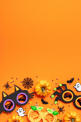 Wall Mural - Happy Halloween concept. Flat lay composition with spooky party decorations, pumpkins, kids eyeglasses, ghosts, spiders on orange background.