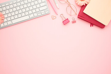 Wall Mural - Flat lay modern workspace with office supplies on pastel pink background. Top view keyboard, glasses, paper notebooks, clips. Education, distance work concept.