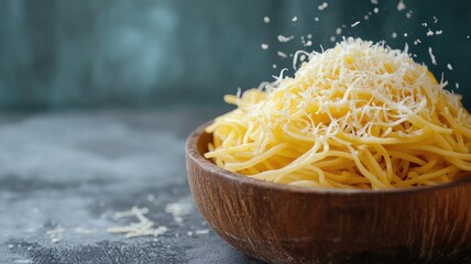 A bowl of noodles topped with a generous sprinkling of grated cheese against a dark background.