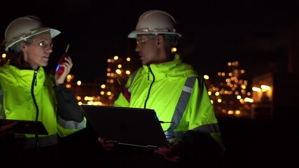 Wall Mural - Team Engineer working at night shift with laptop Inside Oil Refinery Gas Chemical plant. Senior Engineer wearing safety jacket and PPE working about Petrochemica Chemical Prodiction