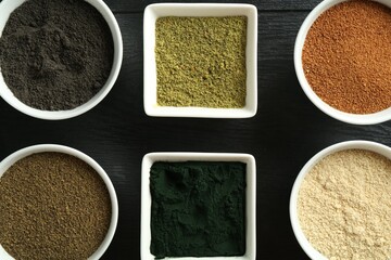 Wall Mural - Different superfood powders in bowls on black wooden table, flat lay