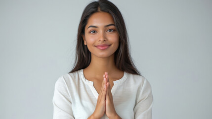 Wall Mural - Young indian woman doing namaste on white background