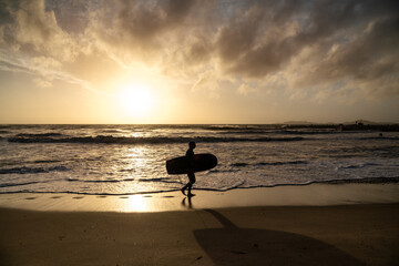 silhouette of a surfer on the beach at sunset