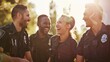 © VK Studio - Four police officers, standing together and laughing, share a moment of camaraderie under the warm glow of the sun.