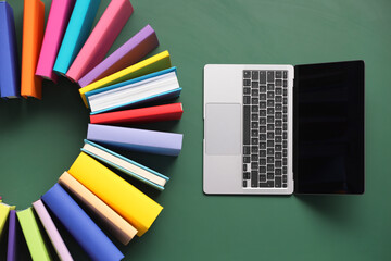 Wall Mural - Many colorful books and laptop on green background, flat lay