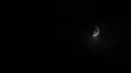 Wall Mural - Fast motion of first quarter moon or waxing gibbous moving among mysterious clouds at night. Telephoto view, real midnight footage with black background. Creepy halloween sky, astrology concept.