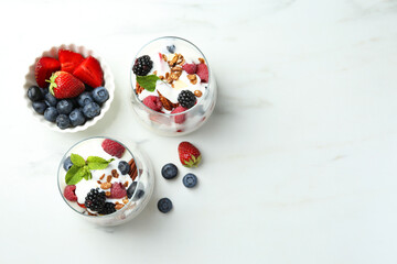 Wall Mural - Tasty yogurt with fresh berries, granola and mint in glasses on white marble table, flat lay. Space for text