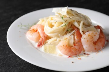 Wall Mural - Delicious pasta with shrimps and cheese on black table, closeup