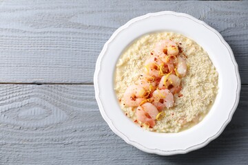 Wall Mural - Delicious risotto with shrimps and cheese on grey wooden table, top view. Space for text